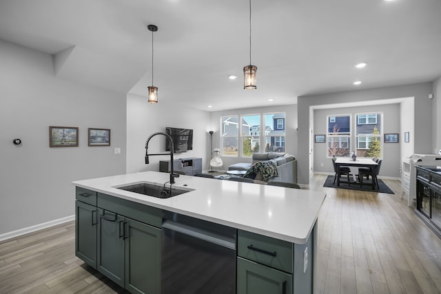 kitchen with a sink, light countertops, dishwasher, green cabinets, and light wood-type flooring