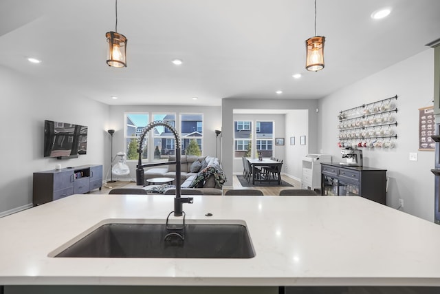 kitchen with light stone countertops, recessed lighting, a sink, decorative light fixtures, and open floor plan