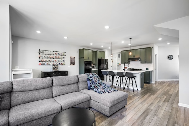 living room with light wood-style flooring, recessed lighting, baseboards, and a dry bar