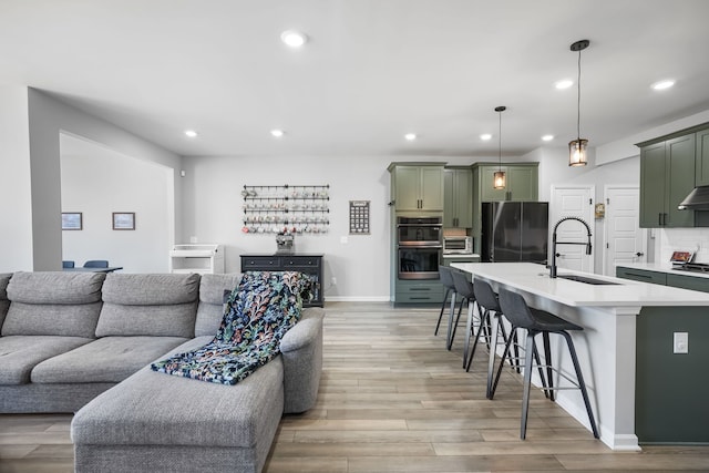 living area featuring recessed lighting, baseboards, light wood-style flooring, and a toaster