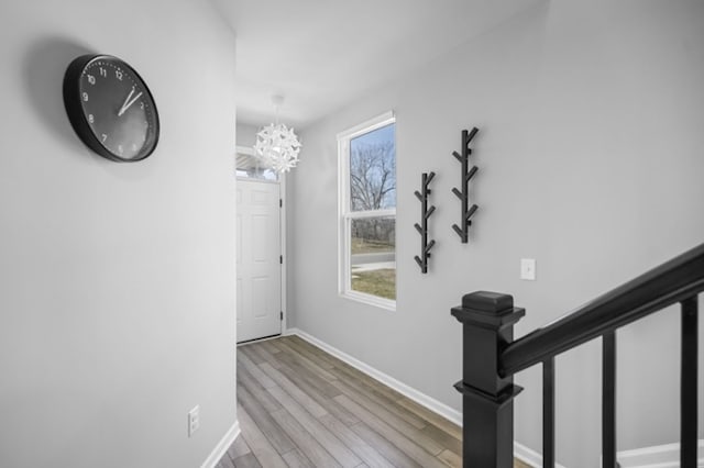 hall featuring a chandelier, baseboards, and wood finished floors