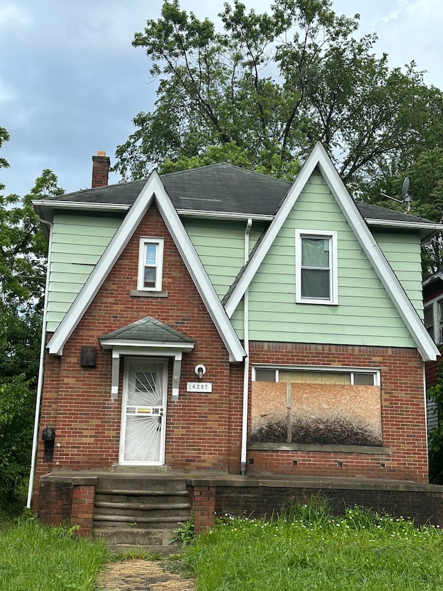 view of front of property with entry steps, roof with shingles, a chimney, and brick siding