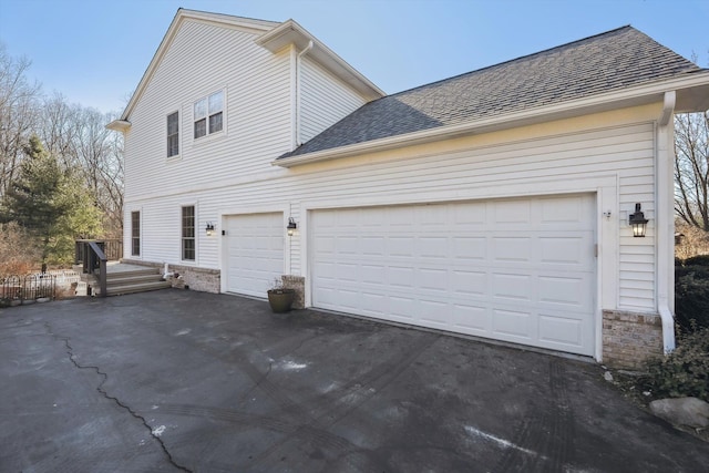 exterior space featuring aphalt driveway, brick siding, and roof with shingles