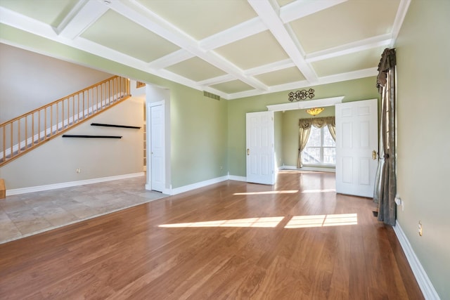 unfurnished living room featuring visible vents, baseboards, stairway, wood finished floors, and coffered ceiling