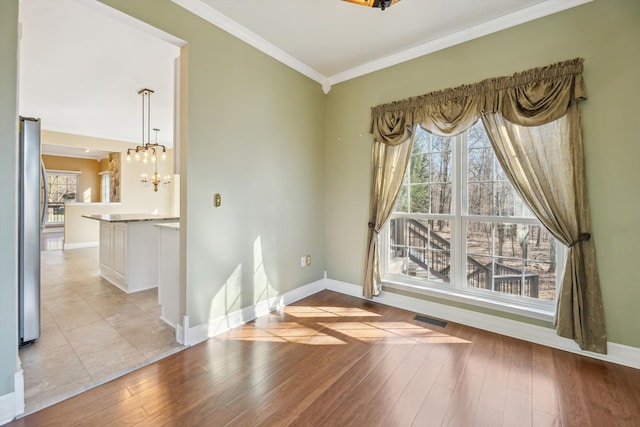 unfurnished room with visible vents, baseboards, light wood-style flooring, and ornamental molding