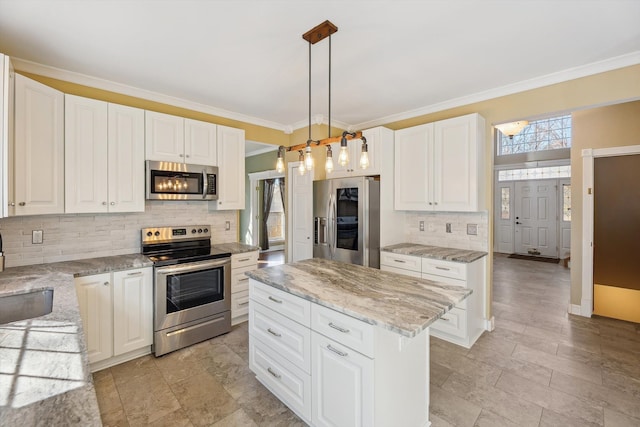 kitchen featuring white cabinets, appliances with stainless steel finishes, a kitchen island, and crown molding