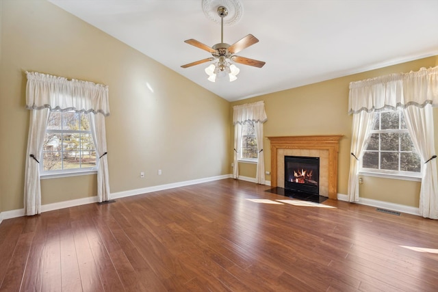 unfurnished living room with baseboards, visible vents, lofted ceiling, a fireplace, and hardwood / wood-style flooring