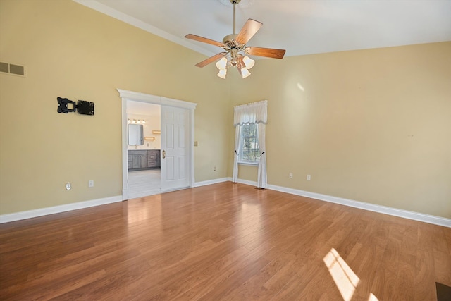 empty room with visible vents, baseboards, wood finished floors, high vaulted ceiling, and a ceiling fan