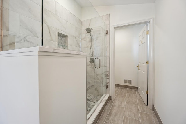 bathroom featuring visible vents, a stall shower, and baseboards