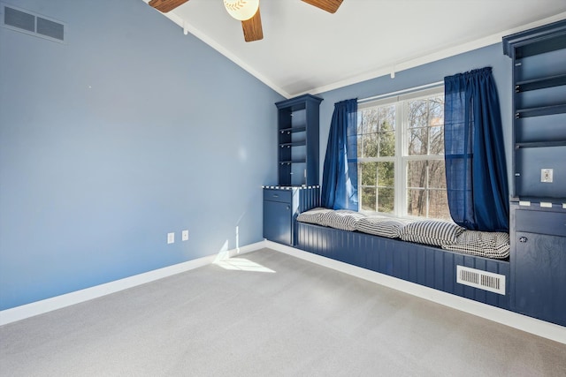 empty room with visible vents, ornamental molding, carpet floors, baseboards, and vaulted ceiling