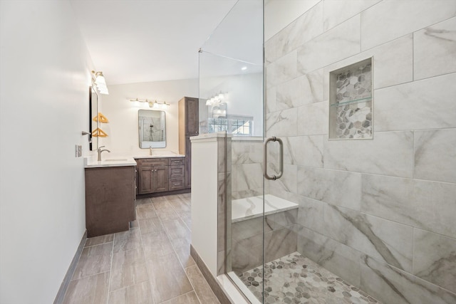 full bathroom with baseboards, a shower stall, vanity, and lofted ceiling