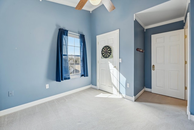 carpeted entrance foyer featuring ceiling fan, baseboards, and ornamental molding