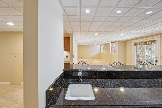 kitchen featuring dark stone counters, recessed lighting, carpet, and a sink