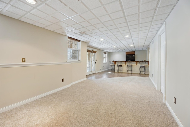 unfurnished living room with recessed lighting, baseboards, carpet floors, and bar area