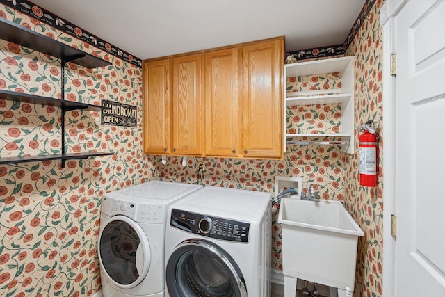 laundry area featuring a sink, cabinet space, washing machine and dryer, and wallpapered walls