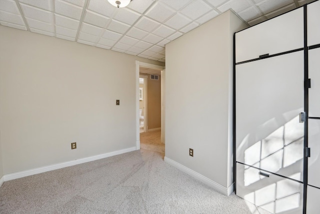 unfurnished room featuring a drop ceiling, visible vents, baseboards, and carpet flooring