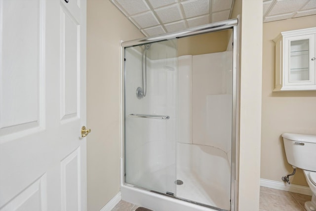 full bathroom featuring tile patterned flooring, a shower stall, toilet, and baseboards