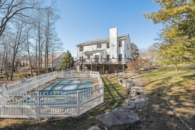 back of property featuring fence, a fenced in pool, a chimney, a deck, and a lawn