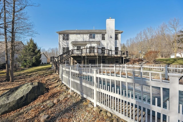 back of property featuring a wooden deck, a chimney, stairs, and fence