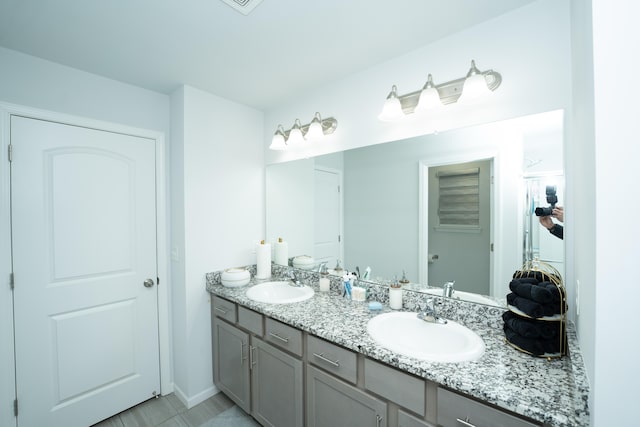 bathroom featuring double vanity, baseboards, and a sink