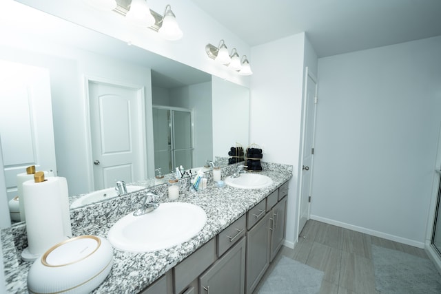 bathroom with a stall shower, a sink, and baseboards