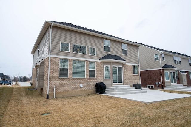 rear view of property with entry steps, a yard, brick siding, and central AC