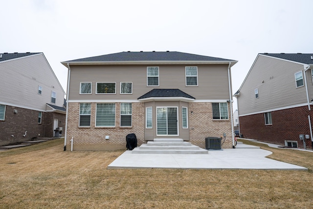 back of house featuring entry steps, a patio, central AC unit, brick siding, and a yard