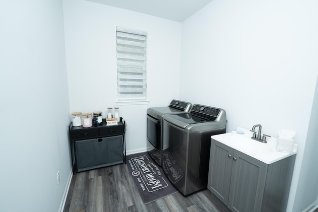 laundry area featuring cabinet space, baseboards, wood finished floors, washing machine and clothes dryer, and a sink