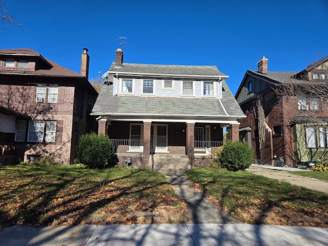 view of front of home featuring a porch, brick siding, and a front lawn