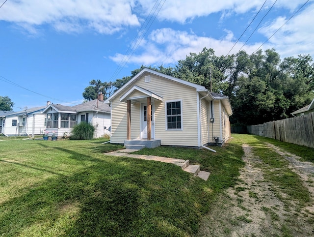 bungalow-style home with a front lawn and fence