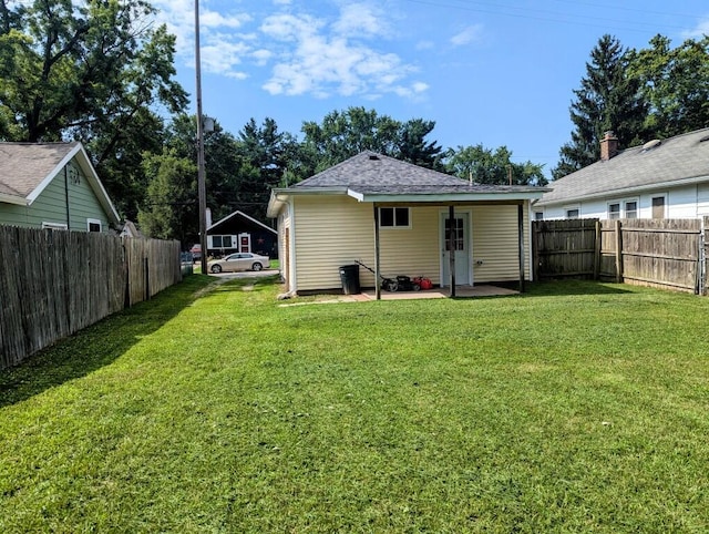 back of property featuring roof with shingles, a fenced backyard, a lawn, and a patio