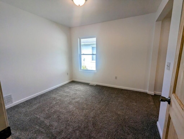 empty room with dark carpet, visible vents, and baseboards