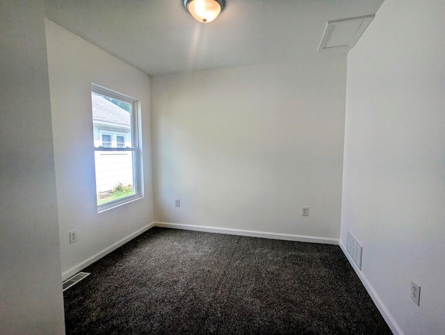 empty room featuring attic access, dark carpet, visible vents, and baseboards