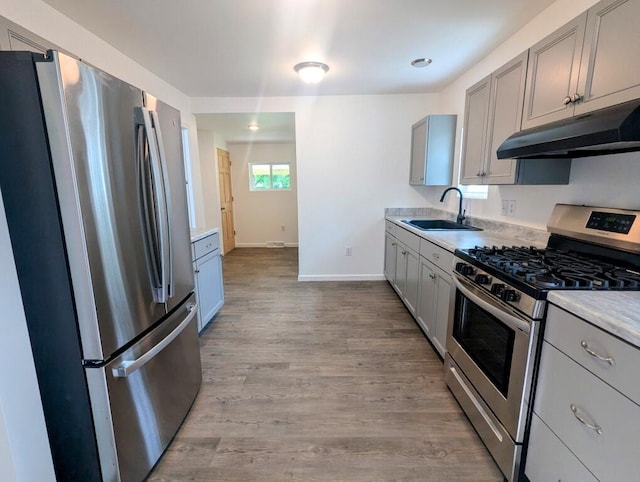 kitchen featuring stainless steel appliances, gray cabinets, a sink, and under cabinet range hood