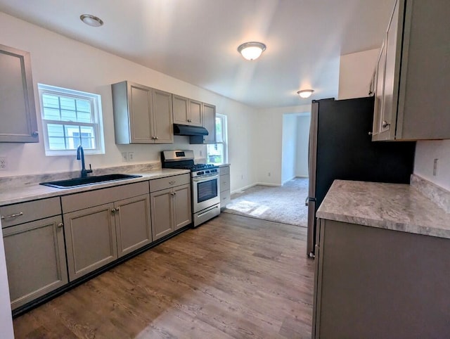 kitchen featuring a sink, gray cabinets, stainless steel range with gas cooktop, and under cabinet range hood