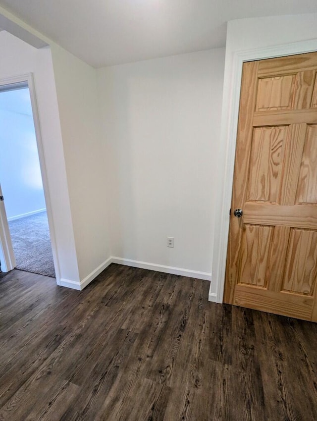 empty room with dark wood-style flooring and baseboards