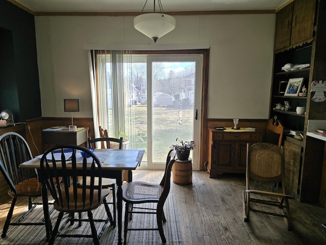 dining room featuring wood-type flooring, ornamental molding, and wainscoting