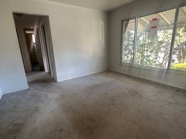 unfurnished room featuring carpet and baseboards