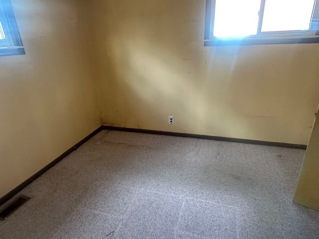 empty room featuring carpet floors, visible vents, and baseboards