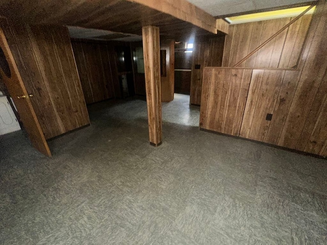 finished basement featuring dark floors and wooden walls