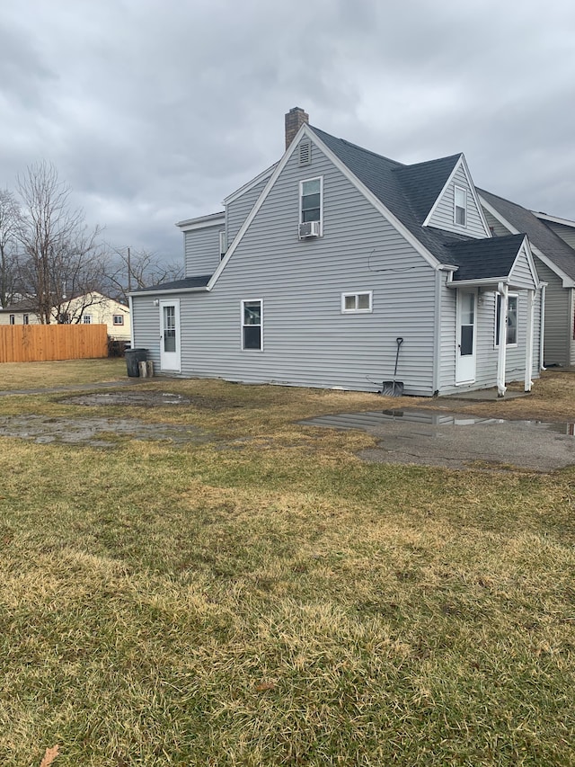 view of home's exterior featuring a chimney, fence, and a lawn