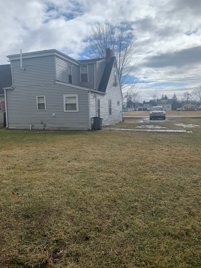 rear view of house featuring a chimney and a yard