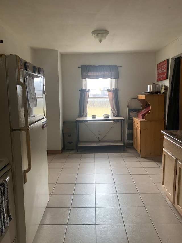 interior space featuring light tile patterned flooring and freestanding refrigerator