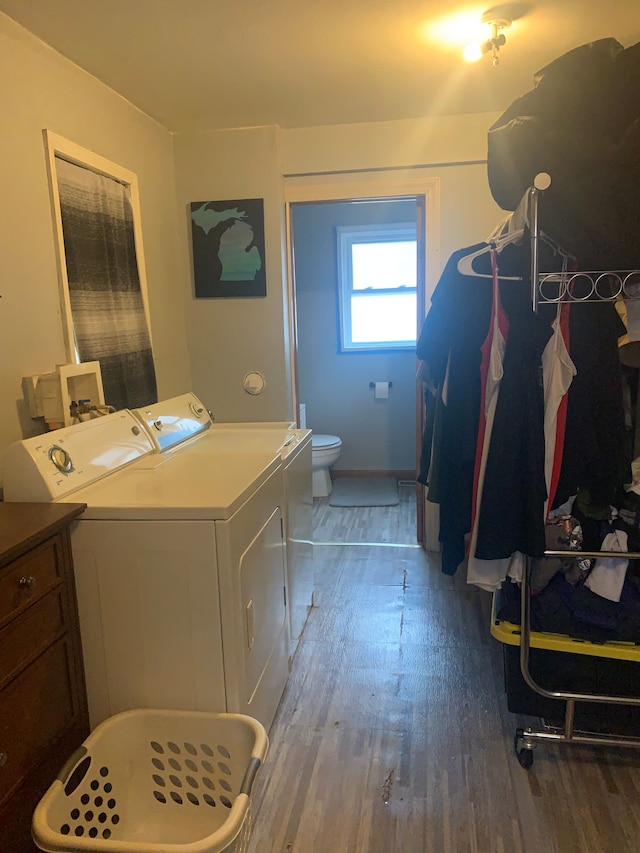 clothes washing area featuring laundry area, washer and clothes dryer, and wood finished floors