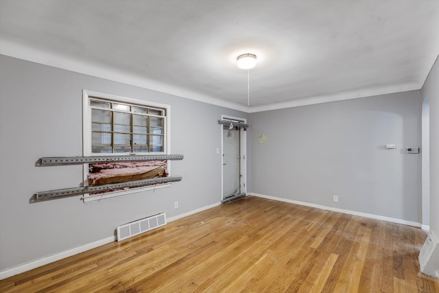 spare room with visible vents, baseboards, and wood finished floors