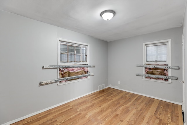 spare room featuring wood finished floors, visible vents, and baseboards