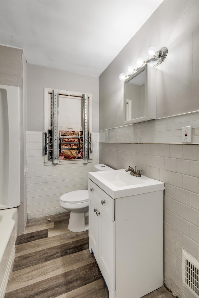 full bath featuring visible vents, wainscoting, toilet, wood finished floors, and vanity