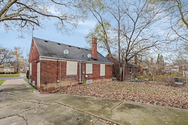 rear view of property with brick siding, roof with shingles, a chimney, crawl space, and fence