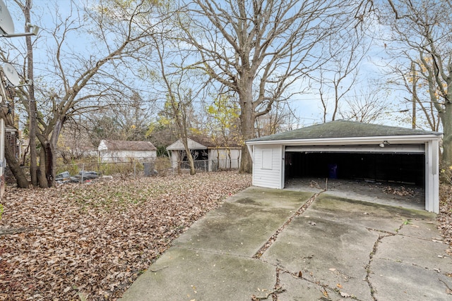 exterior space with a detached garage, fence, and an outbuilding