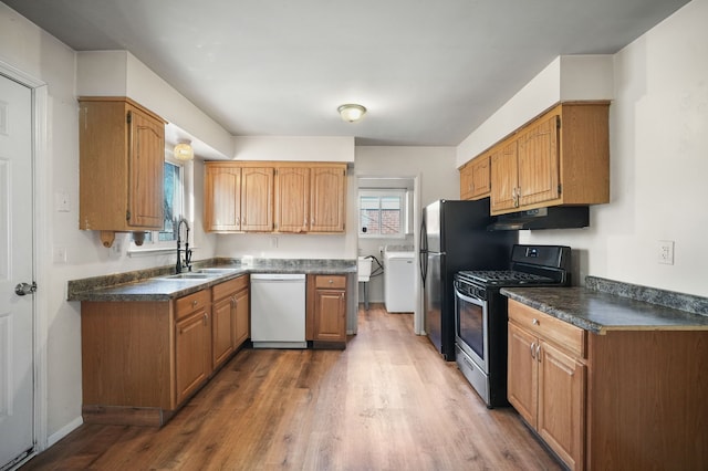 kitchen with stainless steel gas range, washer / clothes dryer, white dishwasher, a sink, and under cabinet range hood